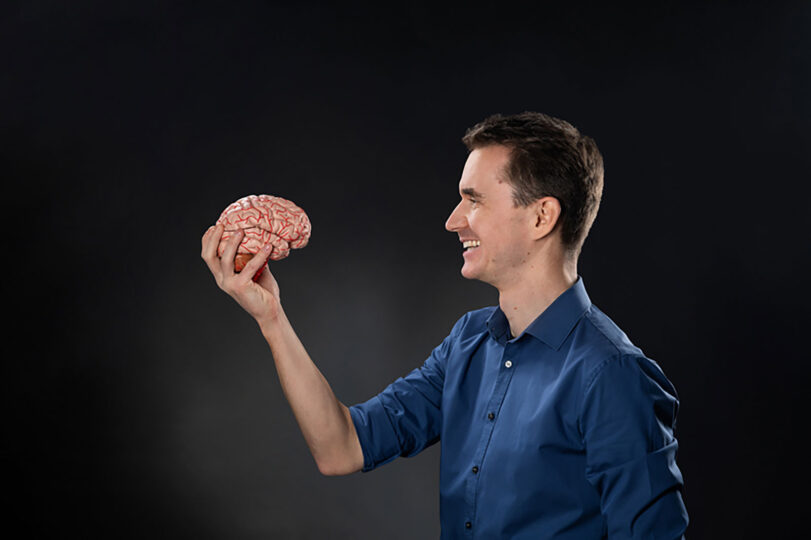 Mann der ein Modell-Gehirn in der Hand hält