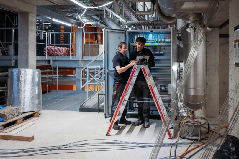 Zwei Elektrofachkräfte kontrollieren und testen einen installierten Schaltschrank